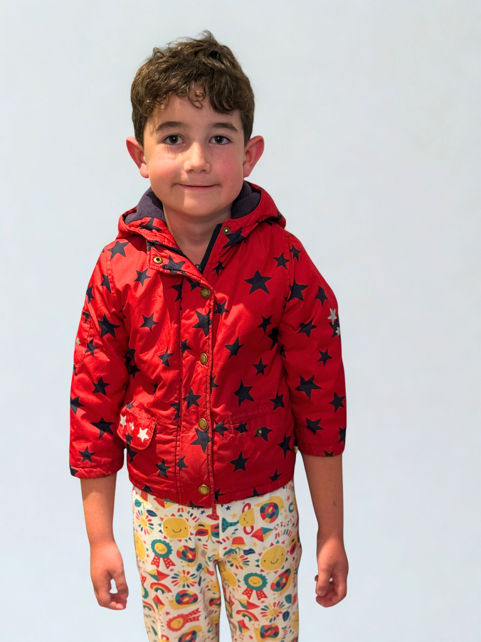 Three children sitting on a stairs wearing bright organic cotton clothing